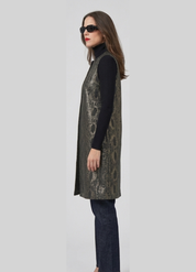 Woman wearing a patterned vest over a black turtleneck and jeans on a light gray background