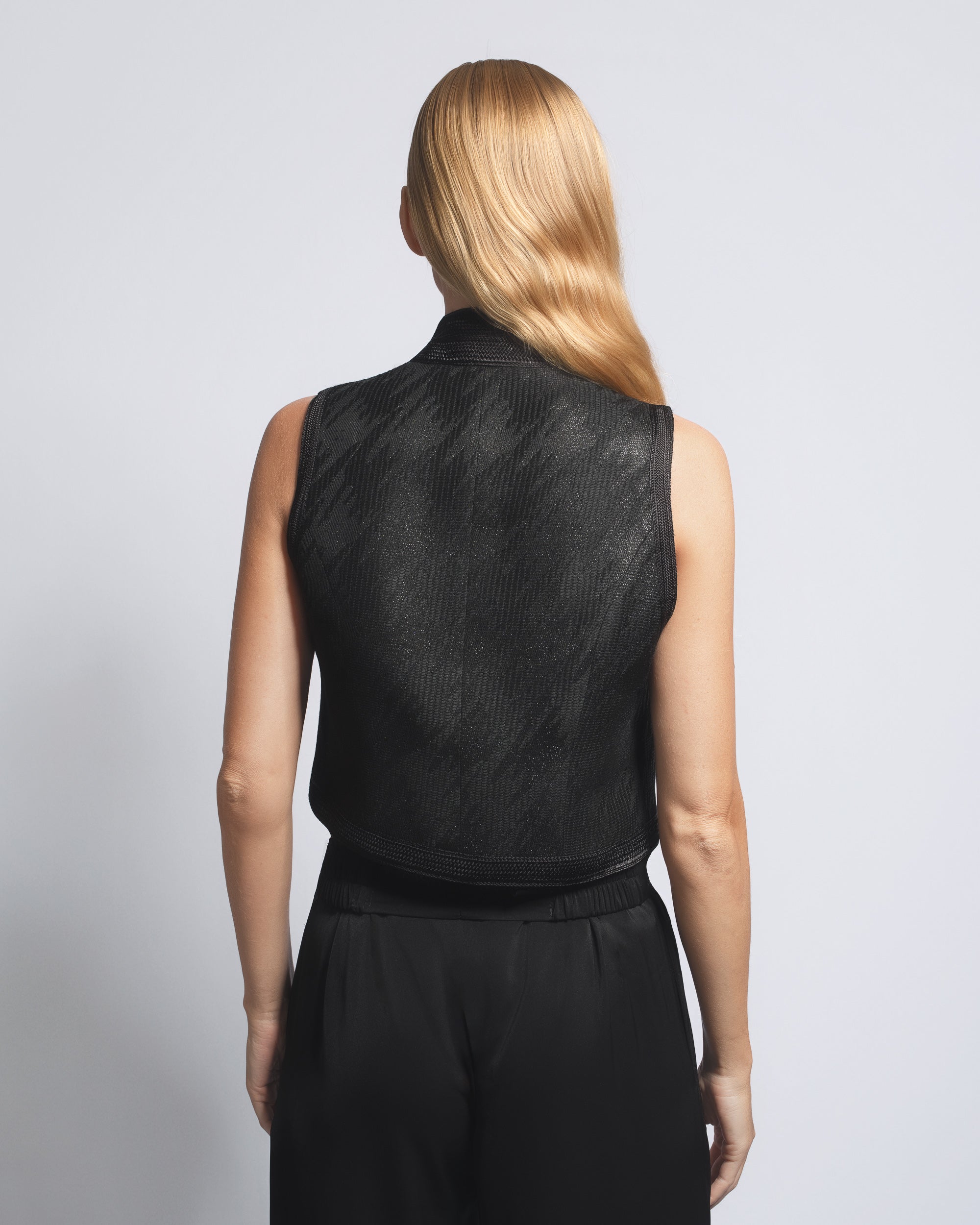 Person wearing a black sleeveless top and skirt set on a plain background