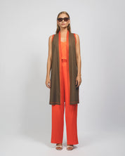 Woman wearing a brown and orange outfit with a long scarf on a white background