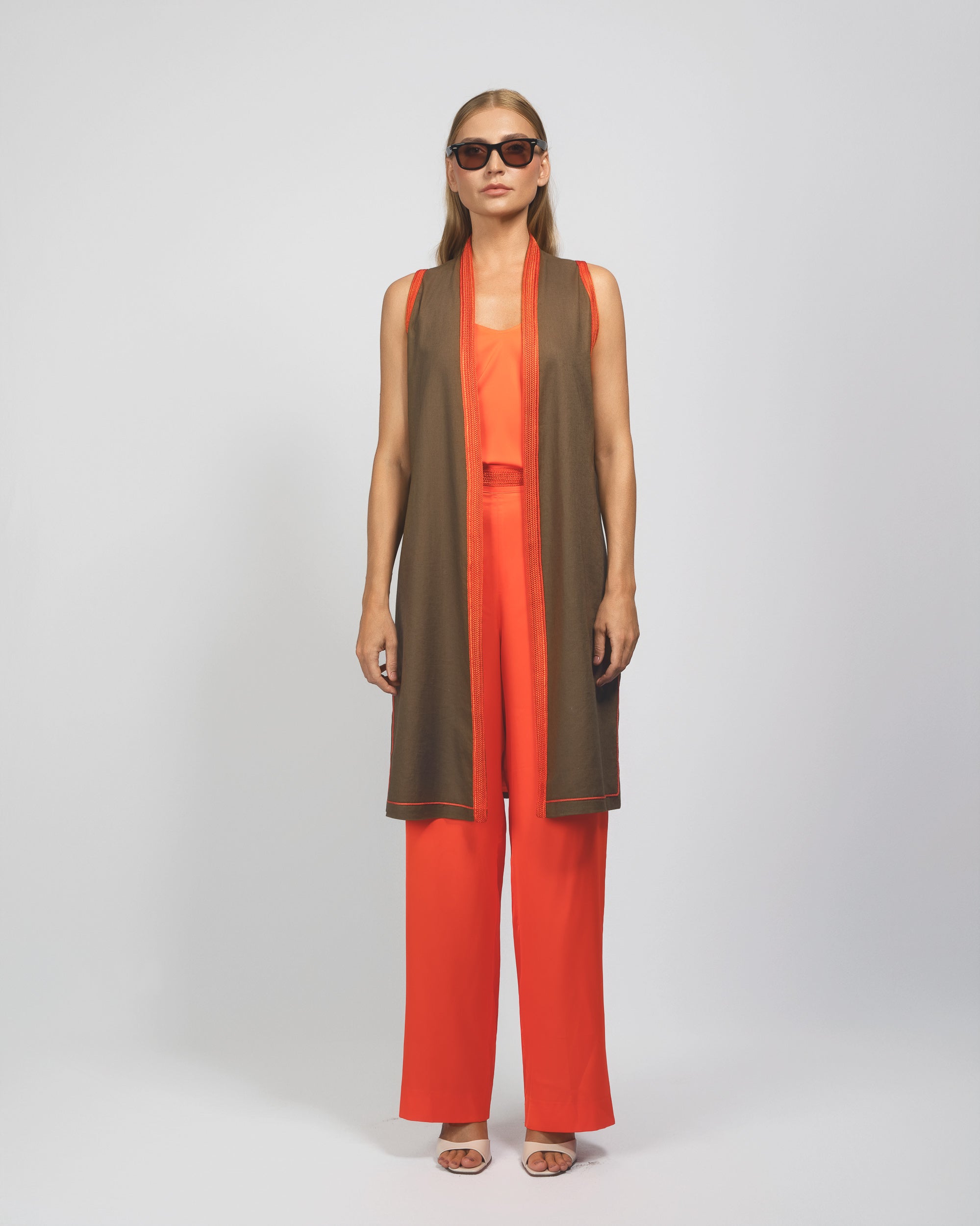 Woman wearing a brown and orange outfit with a long scarf on a white background