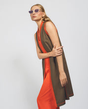 Woman wearing a brown and orange dress with sunglasses on a light gray background