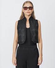 Person wearing a black vest over a black top on a white background