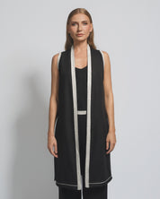 Woman wearing a black sleeveless dress with white trim against a gray background