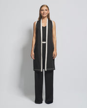Woman wearing a black and white outfit with a long vest on a gray background