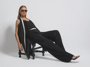 Woman in a black outfit sitting on a chair against a white background