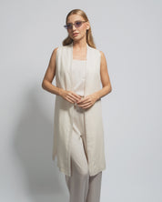 Woman wearing a beige sleeveless dress against a plain background