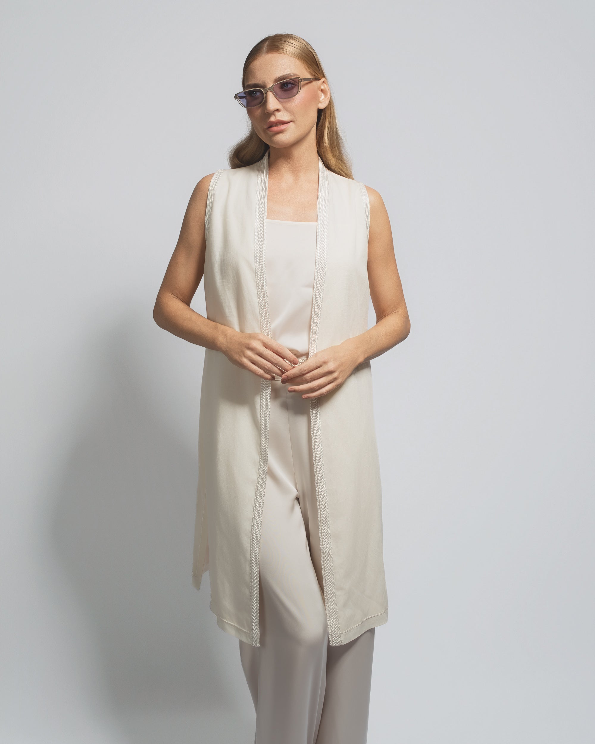 Woman wearing a beige sleeveless dress against a plain background