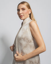 Woman wearing a sleeveless patterned top against a plain background