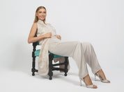 Woman sitting on a chair wearing a white outfit with a plain background