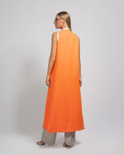 Person wearing an orange sleeveless dress on a plain background
