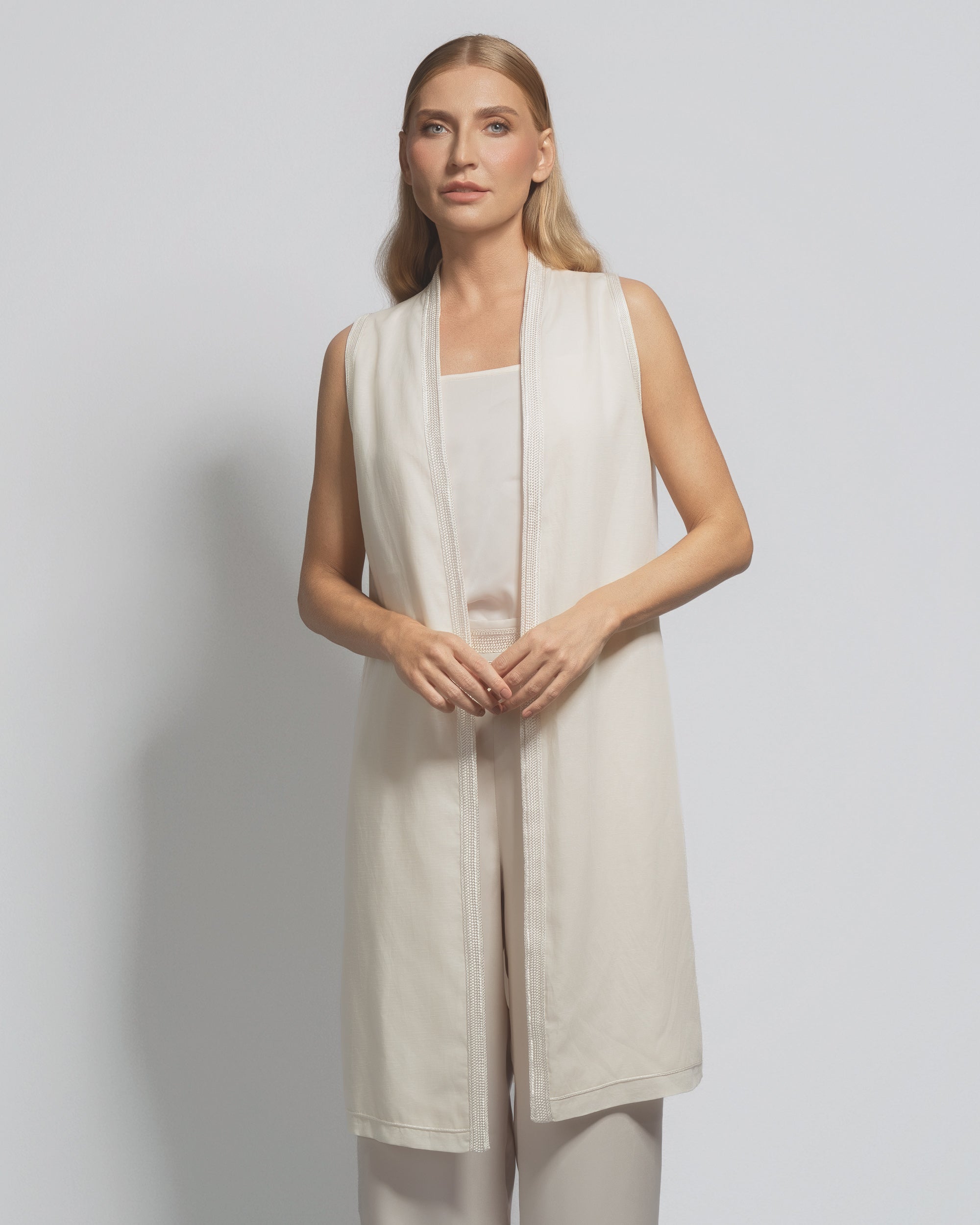 Woman wearing a beige sleeveless dress against a plain background